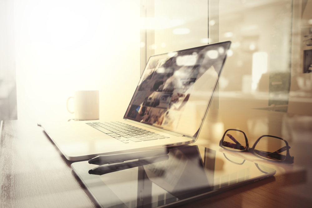 Office-workplace-with-laptop-and-smart-phone-on-wood-table-and-london-city-blurred-background
